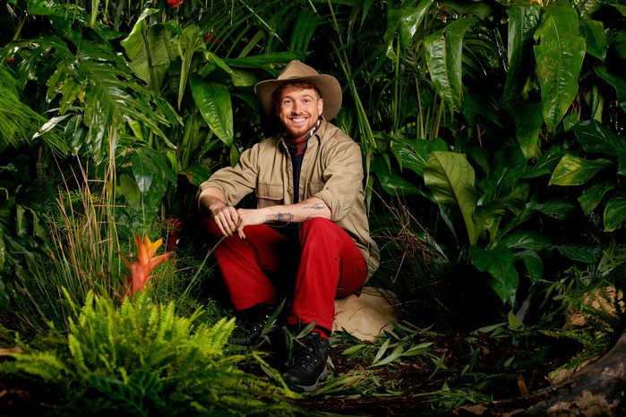 Sam Thompson dressed in his I'm a Celebrity camp gear as he poses in front of some trees ahead of the 2023 show.